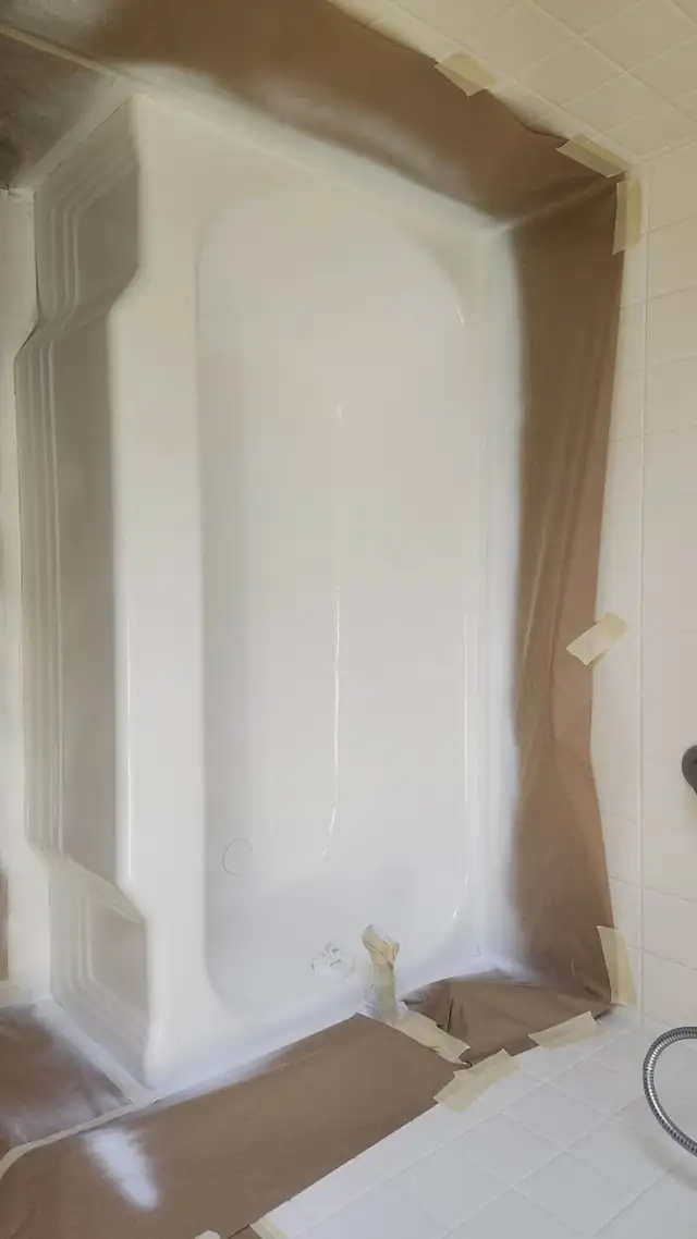 Tub masked with brown paper during a B&J Refinishing job, freshly coated in white